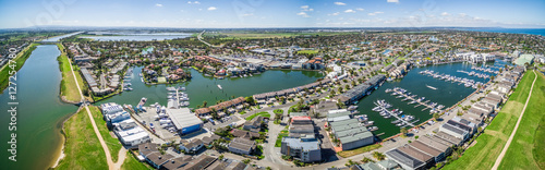 Aerial panorama of Patterson River and Patterson Lakes suburb on bright sunny day. Houses nested near water with moored boats nearby. Melbourne  Victoria  Australia