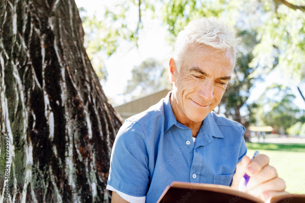 Senior man sittingin park while reading book Senior man sittingin park while reading book