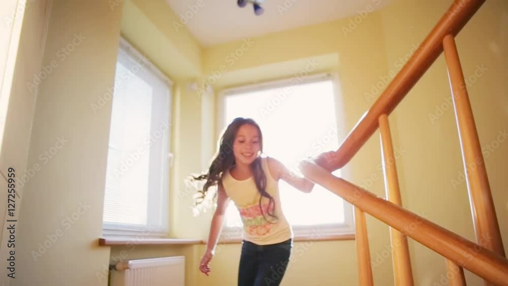 One by one curly girls going down the wooden stairs, they are playing. Happy memories. Joyful time together. Childhood smiling. Inside shooting, yellow walls, white windows on the background. One by one curly girls going down the wooden stairs, they are playing. Happy memories. Joyful time together. Childhood smiling. Inside shooting, yellow walls, white windows on the background.
