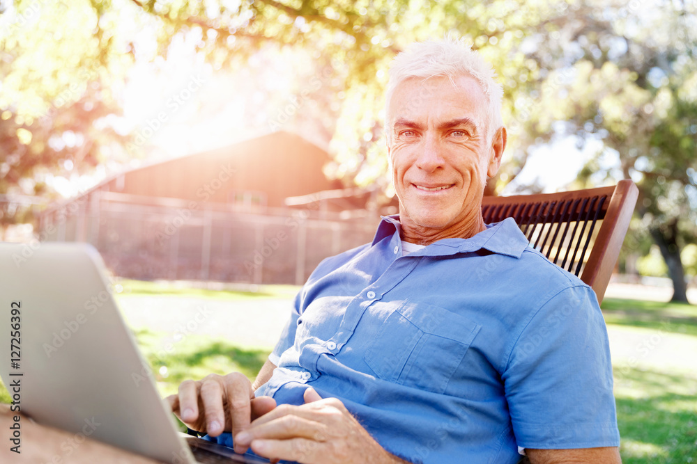 Senior man with notebook sitting in the park Senior man with notebook sitting in the park