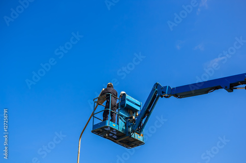 Electrical technician repairing street light by boom lift in industrial 