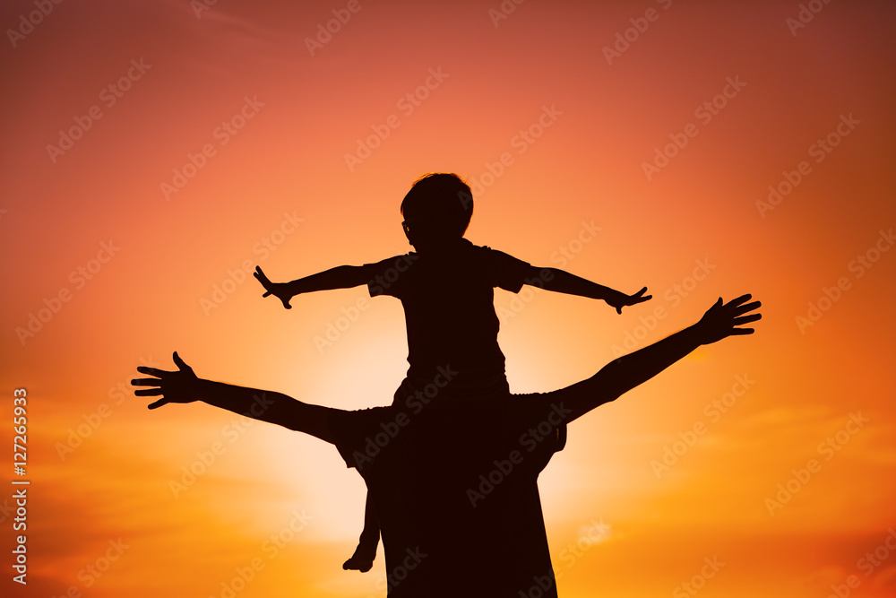 father and son play on sunset sky