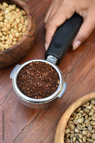 Freshly ground coffee beans in a metal filter and coffee beans for background