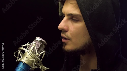 Young man in casual cloth standng behind microphone and making speech