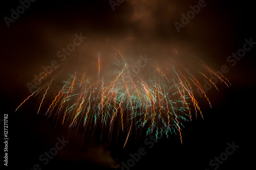 Colorful holiday fireworks in the evening sky with majestic clou