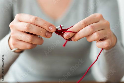 woman knitting with crochet hook and red yarn