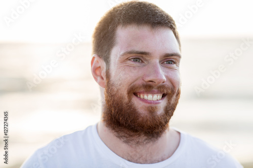 face of happy smiling young man outdoors