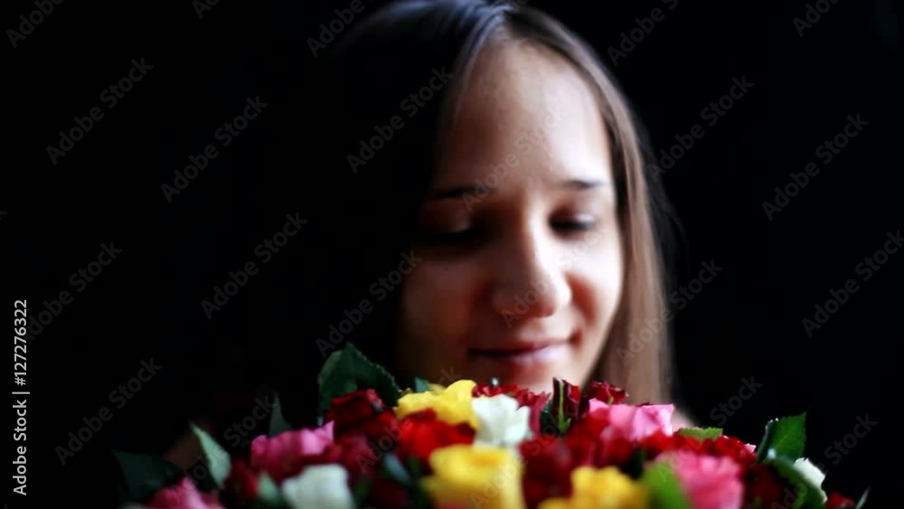 Beautiful smiling woman with a large bouquet of flowers in her arms smelling a fragrant colorful roses on black background. 1920x1080 Beautiful smiling woman with a large bouquet of flowers in her arms smelling a fragrant colorful roses on black background. 1920x1080