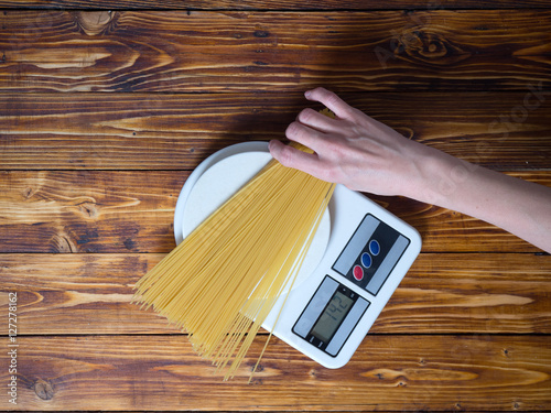 Girl is preparing pasta and weighs it on scales
