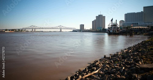 New Orleans, Louisiana, USA - on the banks of the Mississippi River with Steamboat at the pier and Crescent City Connection Bridge at sunny day - Timelapse with zoom out