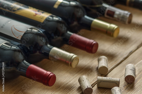 Row of red dry wine bottles and wine corks  on wooden background. Low depth of field.  photo