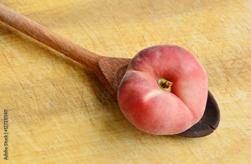 Dough nut peaches also known as Saturn peach withwooden spoon on wooden board.
Benefits of Dough nut peaches. photo