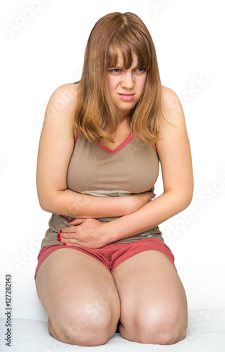 Young woman sitting on the bed with stomach pain