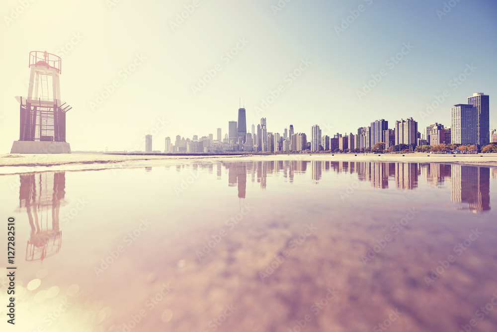 Retro toned sunrise in Chicago, city skyline reflected in a puddle, USA.