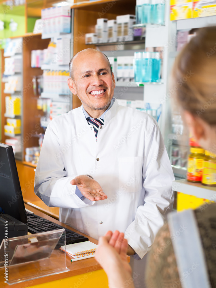 Pharmaceutist helping young woman in drugstore