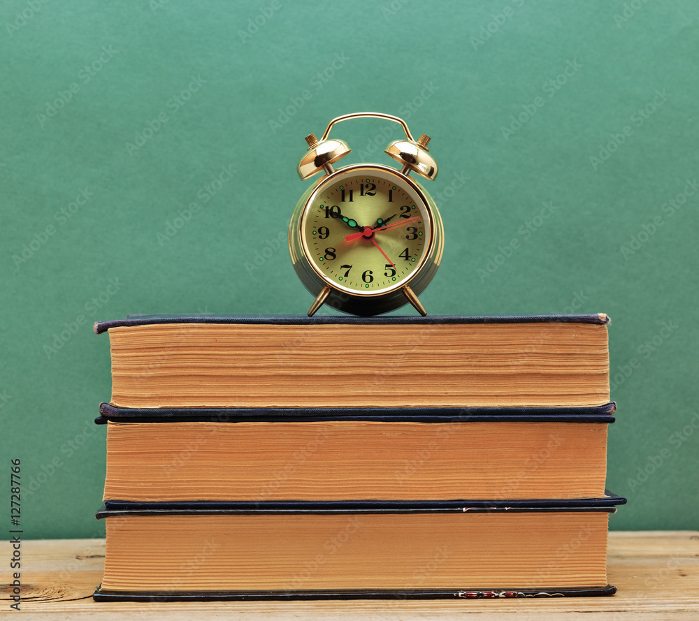 old books on a wooden shelf and alarm clock old books on a wooden shelf and alarm clock