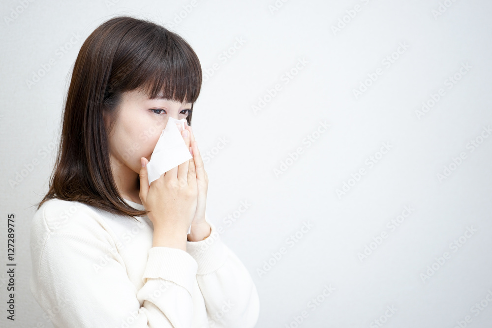 Young woman blowing her nose with tissues Young woman blowing her nose with tissues