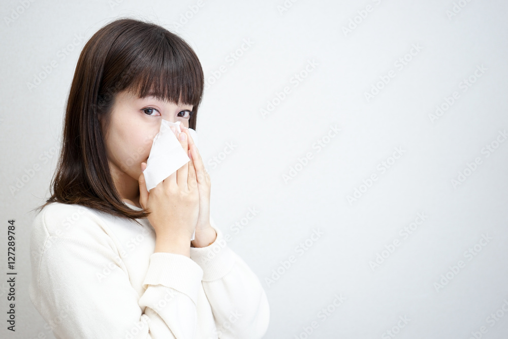 Young woman blowing her nose with tissues Young woman blowing her nose with tissues