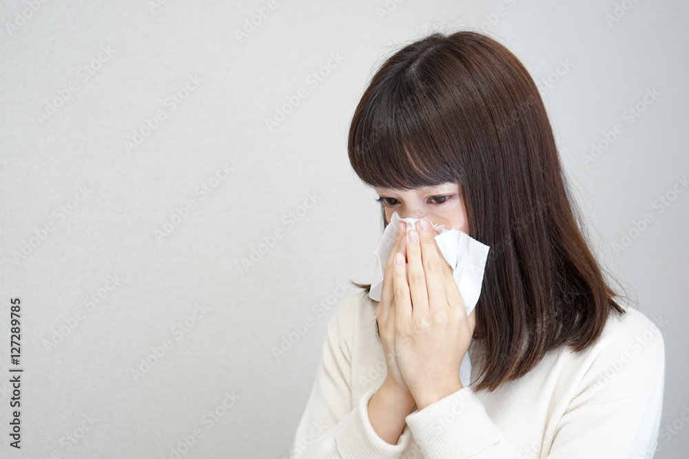 Young woman blowing her nose with tissues Young woman blowing her nose with tissues