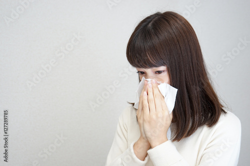 Young woman blowing her nose with tissues