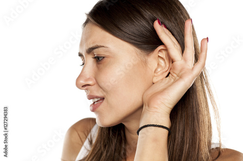 young woman carefully listening with her hand behind her ear