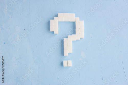 Question mark made of sugar cubes on blue background, symbol ?