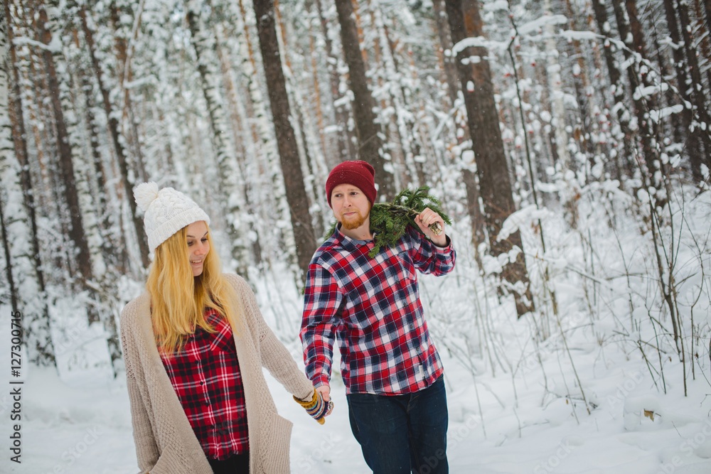 young couple with fir twigs walk in the winter woods