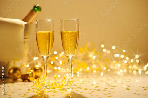 Champagne flutes on table decorated with streamer and gold confe