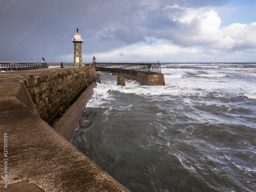 WHITBY, ENGLAND - NOVEMBER 5: East Lighthouse, and rough sea. In Whitby, North Yorkshire, England. On 5th November 2016. WHITBY, ENGLAND - NOVEMBER 5: East Lighthouse, and rough sea. In Whitby, North Yorkshire, England. On 5th November 2016.