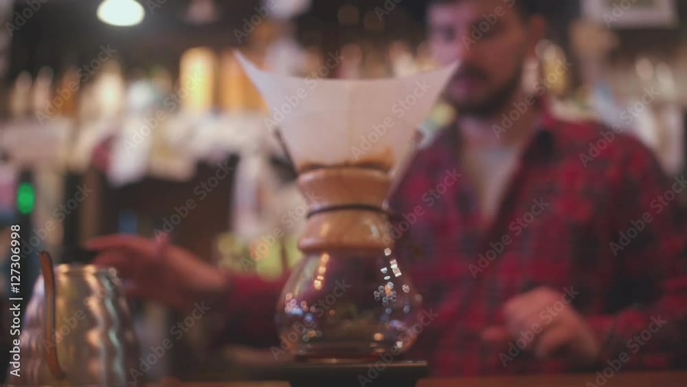 Modern and alternative ways of making coffee. The bartender brews coffee using Coffee maker Chemeks. The bartender puts the filter in Coffee maker Chemeks and pours hot water.