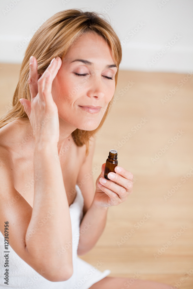 femme qui se masse les tempes avec de l'huile essentielle femme qui se masse les tempes avec de l'huile essentielle