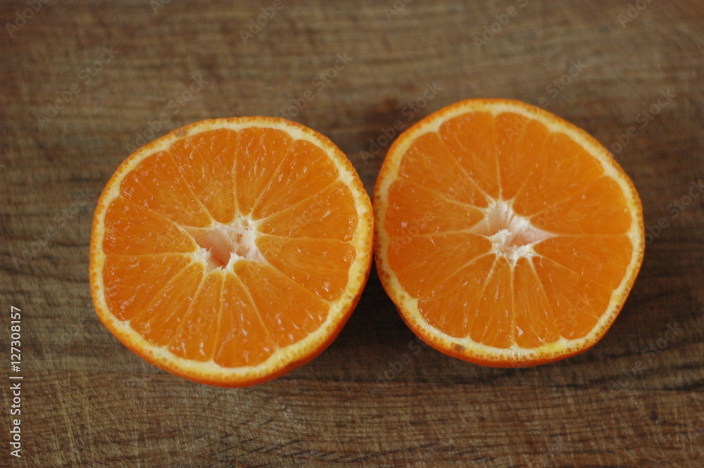 Several mandarin oranges cut in half on a wooden background. Several mandarin oranges cut in half on a wooden background.