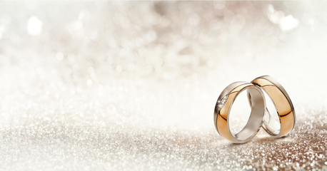 Two gold wedding bands on textured glitter