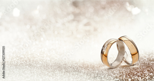 Valokuva Two gold wedding bands on textured glitter