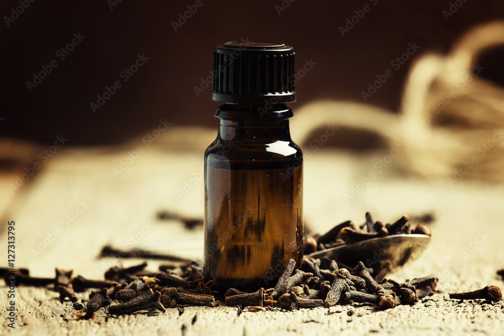 Essential oil of cloves in a brown bottle on a vintage wooden ba Essential oil of cloves in a brown bottle on a vintage wooden ba