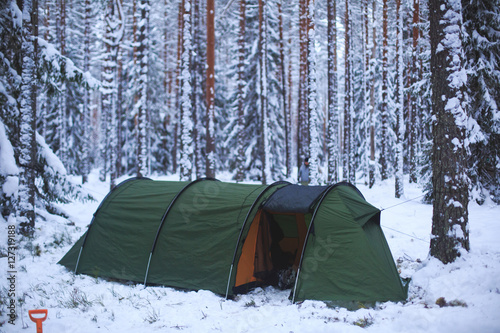 A process of camping in winter forest  setting a tent covered in snow  making a bonfire campfire and cooking food with portable gas cooker and fire  snowy landscape 