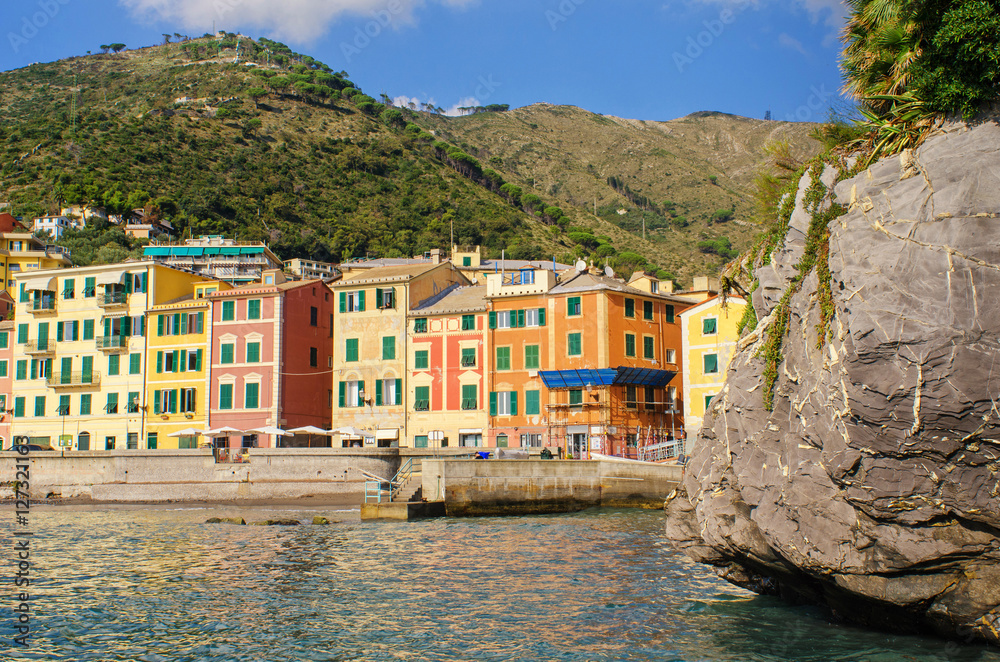 view from the inside of the small Genoa Nervi harbor with hills in the back and one of many surrounding stone structures in the front