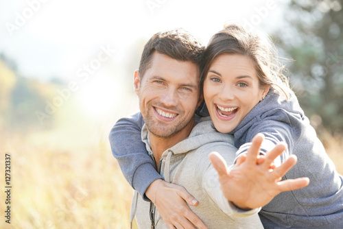 Man giving piggyback ride to girlfriend in countryside