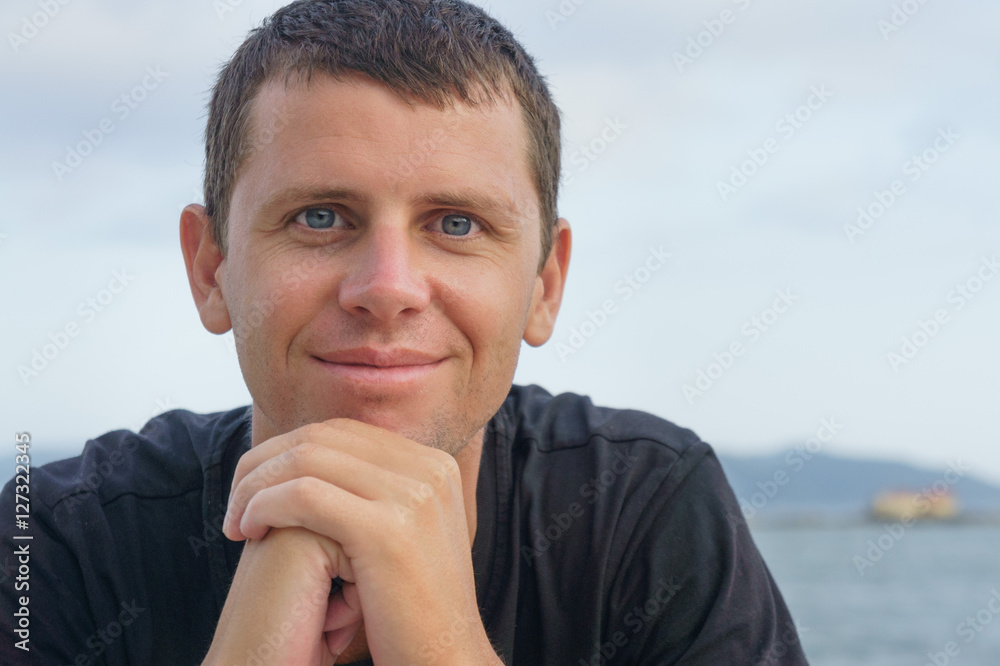 portrait of handsome young man standing against a beach
