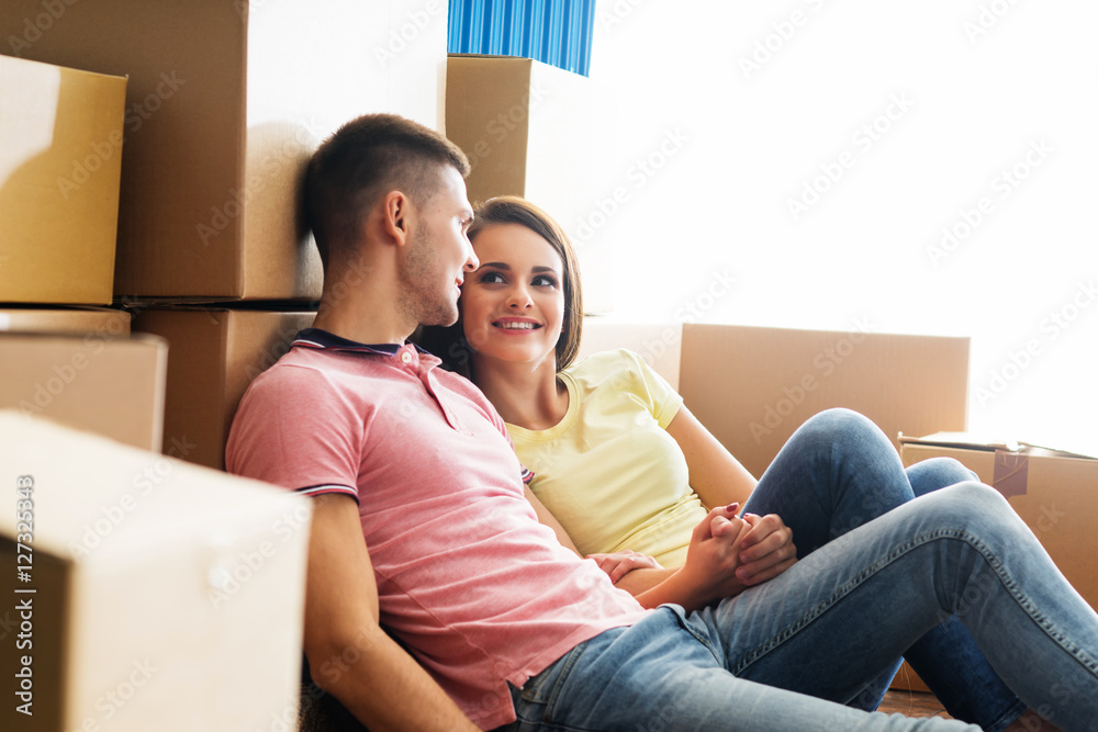 Young couple on the floor next to cardboard boxes Young couple on the floor next to cardboard boxes