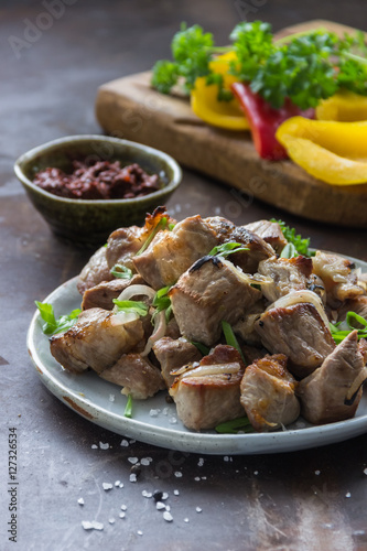 Shish kebab with vegetables on plate and dark stone background. Selective focus