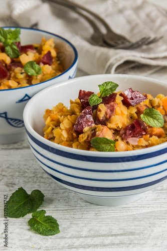 lentil with sausage and vegetables in pot on rustic background, top view