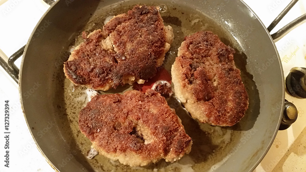 Fresh appetizing meat schnitzel fried in a pan in hot oil Fresh appetizing meat schnitzel fried in a pan in hot oil