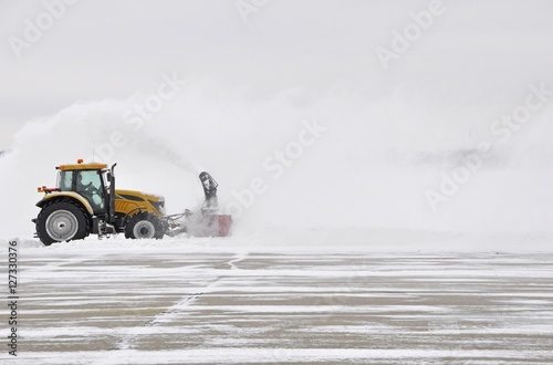 large tractor with snow plow at work during a winter storm