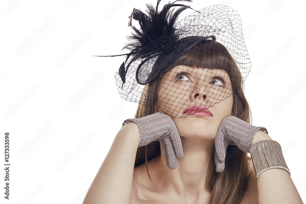 Pensive sad pretty young lady with fringe haircut wearing gloves and black  vintage feather light hat with net veil. Retro styled woman daydreaming  with hands on chin. White background, copy space. foto