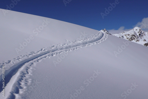 ski tracks in the snow in the Swiss Alps on a clear day with blue sky