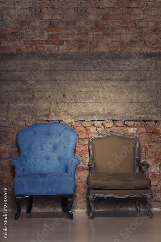 Two antique chairs against a grungy brick wall
