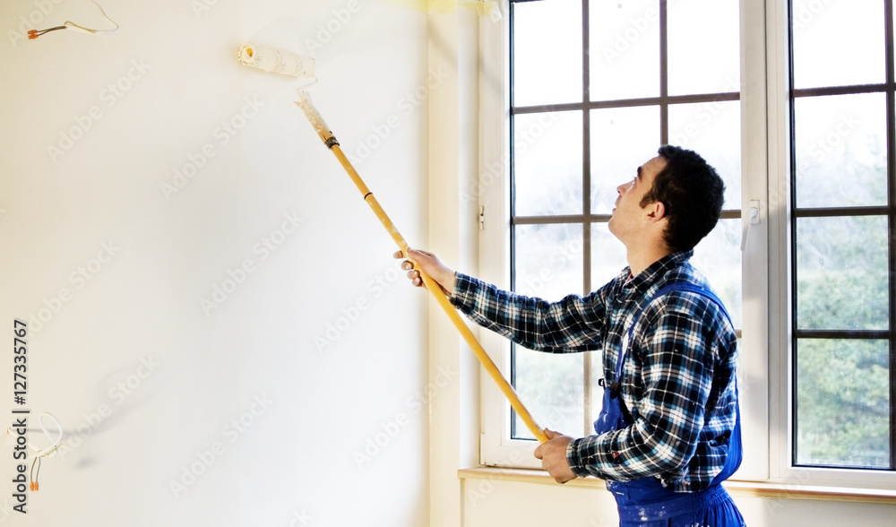 Worker house painter painted the walls in yellow