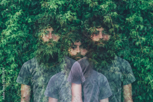 Triple exposure portrait of transparent young man and green foliage