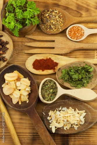 Various kinds of spices on the kitchen table. Seasoning food. Sales of exotic spices. Advertising on spices. Powder spices on spoons in wooden table background.
